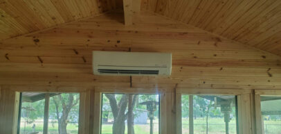 indoor ductless ac unit positioned high on the wood wall above open windows